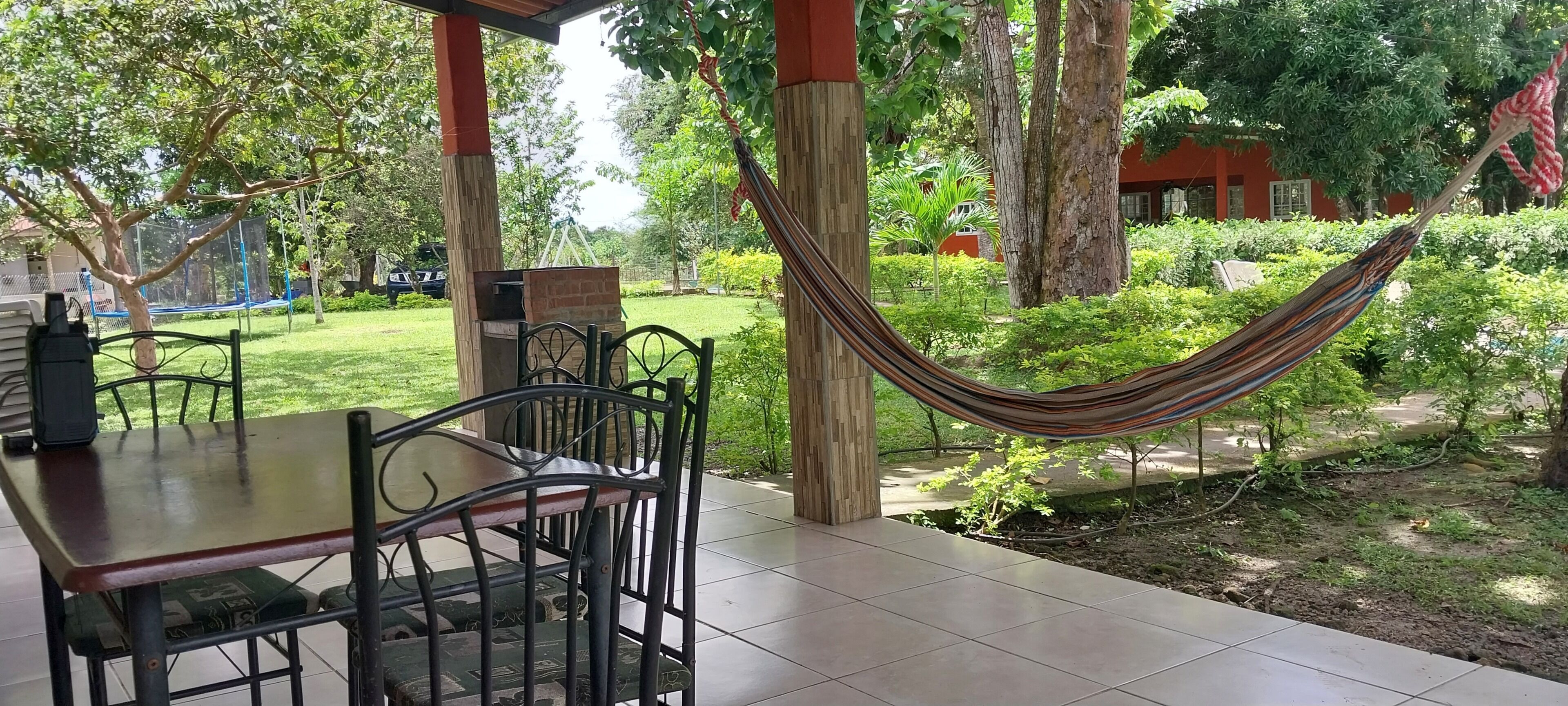 Un patio al aire libre con mesa y sillas, una hamaca y un horno de ladrillo.
