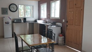 Cocina compacta con refrigerador, microondas, estufa a gas y una mesa de comedor con sillas.