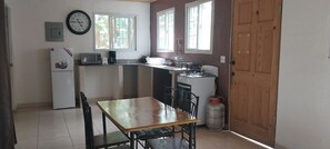 Cocina compacta con refrigerador, microondas, estufa a gas y una mesa de comedor con sillas.