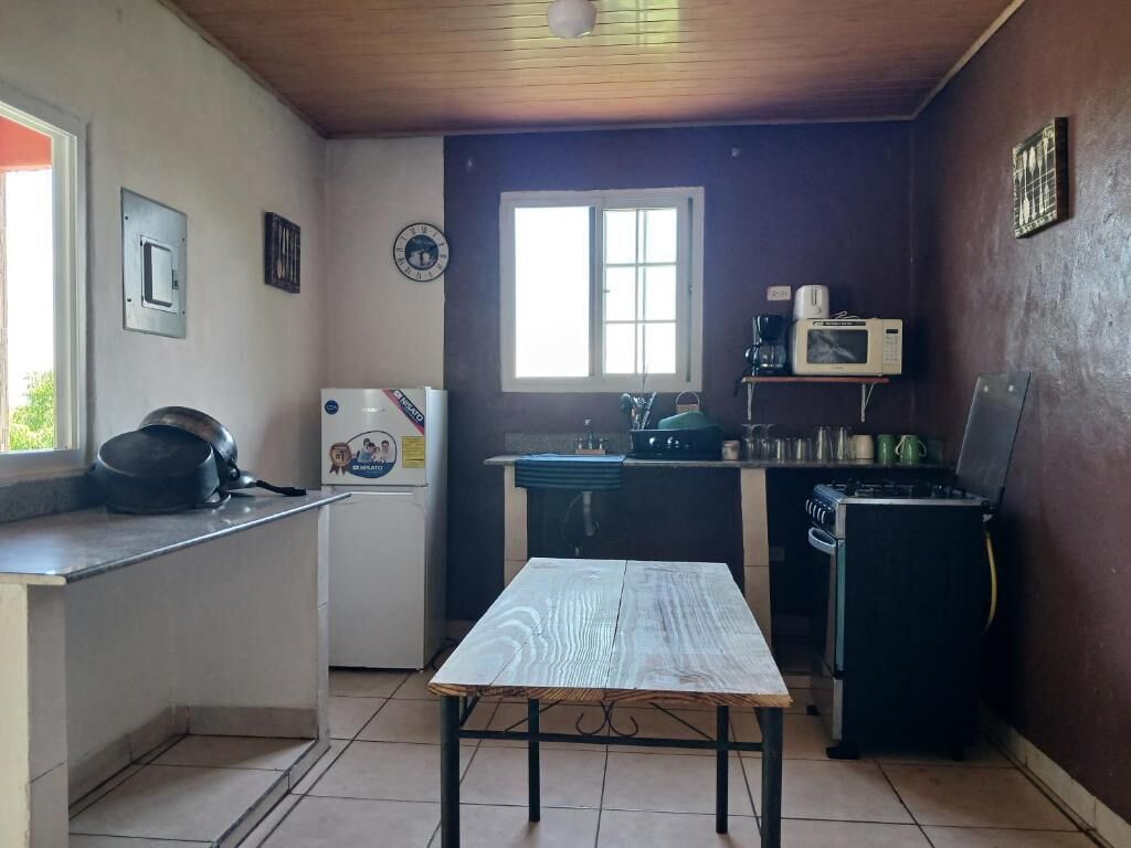 Una cocina compacta con una mesa, microondas y pileta.