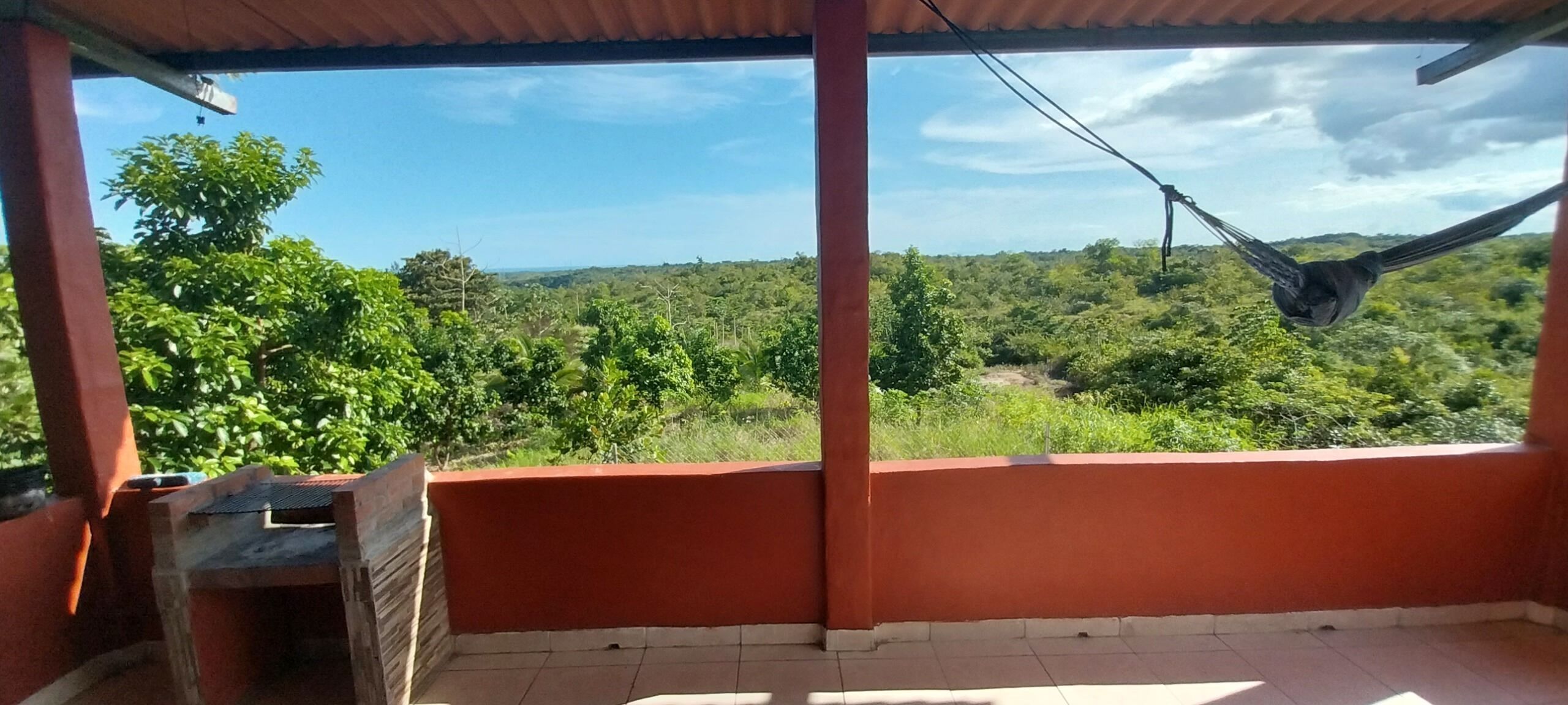 A balcony with a view of a green landscape and a hammock.
