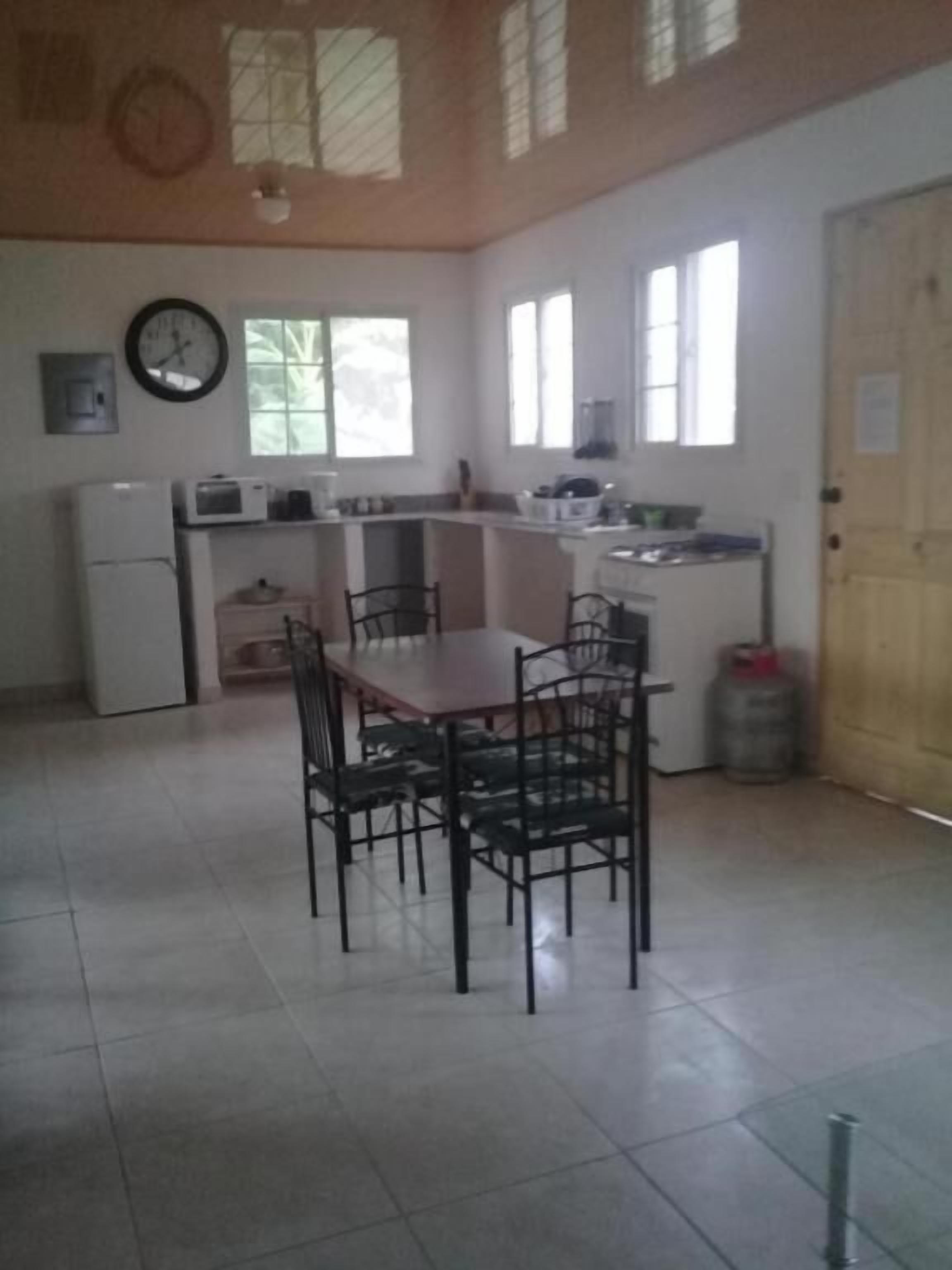 Una cocina con una mesa de comedor y sillas, un refrigerador y un microondas.