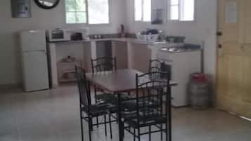 Una cocina con una mesa de comedor y sillas, un refrigerador y un microondas.