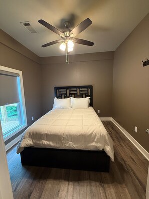 A bedroom with a bed, a ceiling fan, a window, and a view of the outdoors.
