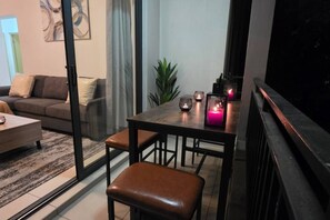 A modern living room with a sofa, a coffee table, and a dining area with a table and chairs. - Stylish 2BR Apartment, Pool & Balcony, Joburg (Midrand)