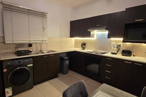 Una cocina compacta equipada con lavadora, fregadero, estufa y microondas.