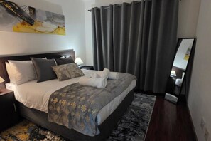 Et hotelværelse med en stor seng, et sengebord, en lampe, et spejl og et billede på væggen.