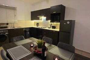 Una cocina compacta con armarios oscuros, un microondas integrado y un refrigerador.
