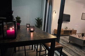 A modern dining area with a wooden table, candles, and a minimalist design. - Stylish 2BR Apartment, Pool & Balcony, Joburg (Midrand)