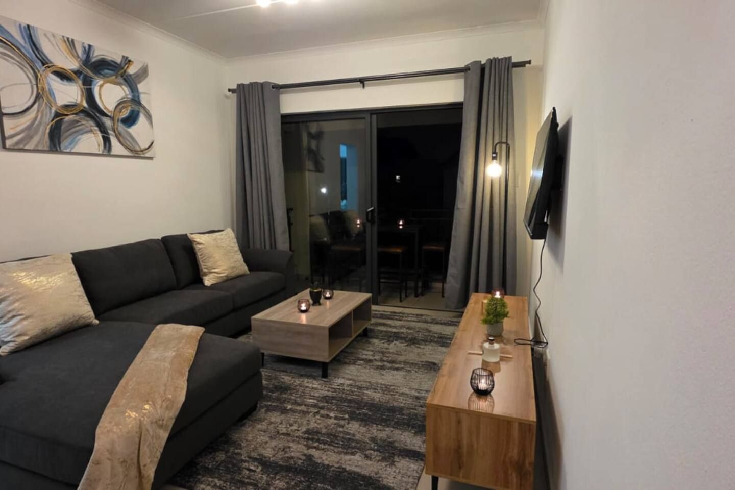 Un saló modern amb un sofà, una taula de centre i un televisor muntat a la paret.