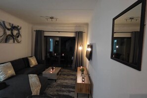 En moderne stue med sofa, sofabord og fjernsyn hængt på væggen.