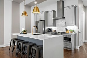 A modern kitchen with a central island, stainless steel appliances, and bar stools. - City View Rooftop Retreat w/ FirePit • Close to DT (Nashville)
