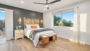 A modern bedroom with a bed, bedside tables, a ceiling fan, and a large window. - The Shire at Baggins Hill by Avantstay Hot Tub + Playhouse + Cornhole 10 Private Acres (Templeton)