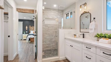 Un baño moderno con ducha, tocador y un espejo grande.