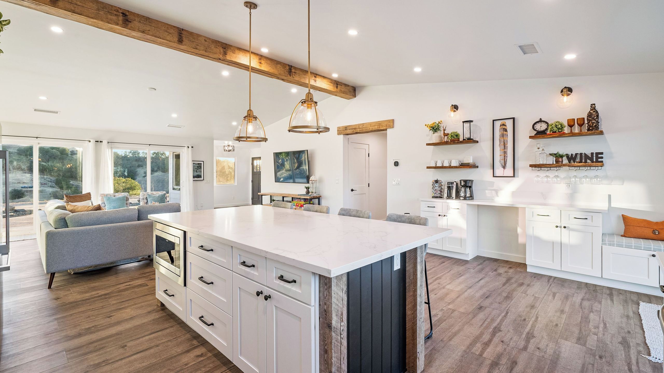 A modern kitchen with a central island, wooden beams, and pendant lighting.