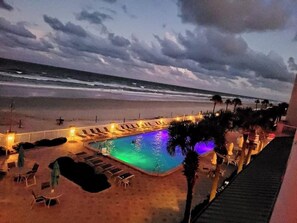 A pool area with lounge chairs and umbrellas, overlooking a beach and ocean. - Surf N Sun spectacular oceanfront studio w/balcony (Daytona Beach)