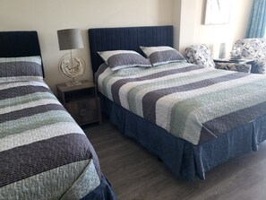 A hotel room with two beds, a nightstand with a lamp, and a chair. - Surf N Sun spectacular oceanfront studio w/balcony (Daytona Beach)