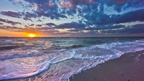 A beach with waves and a sunset.