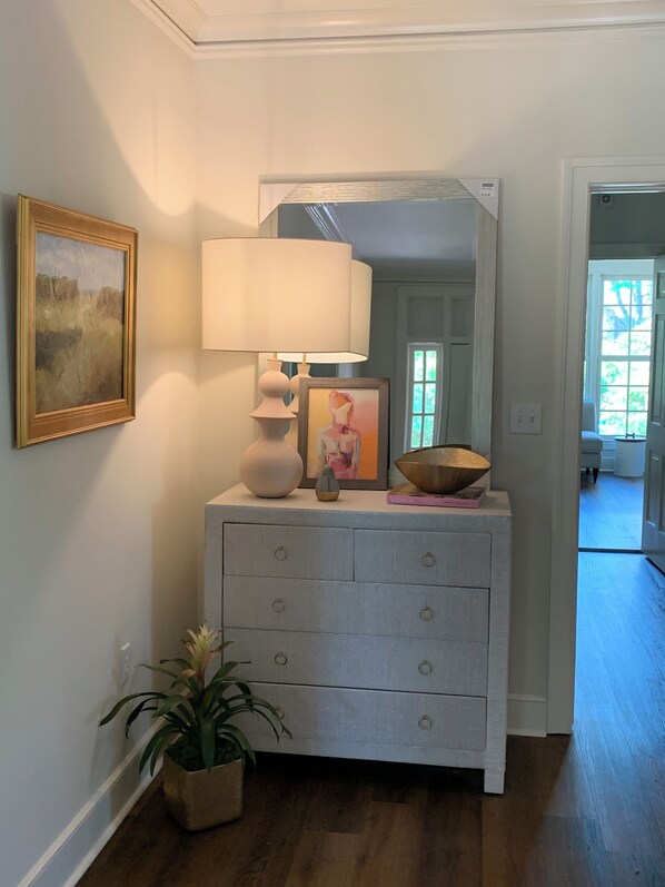 A hallway with a white dresser, a lamp, a framed picture, and a potted plant. - Spacious, Fully Renovated Sumter Home Near CCTC, USC Sumter & Prisma Health (Sumter)