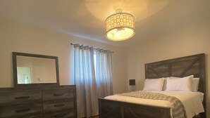 A bedroom with a wooden bed, a dresser, a mirror, and a ceiling light fixture.