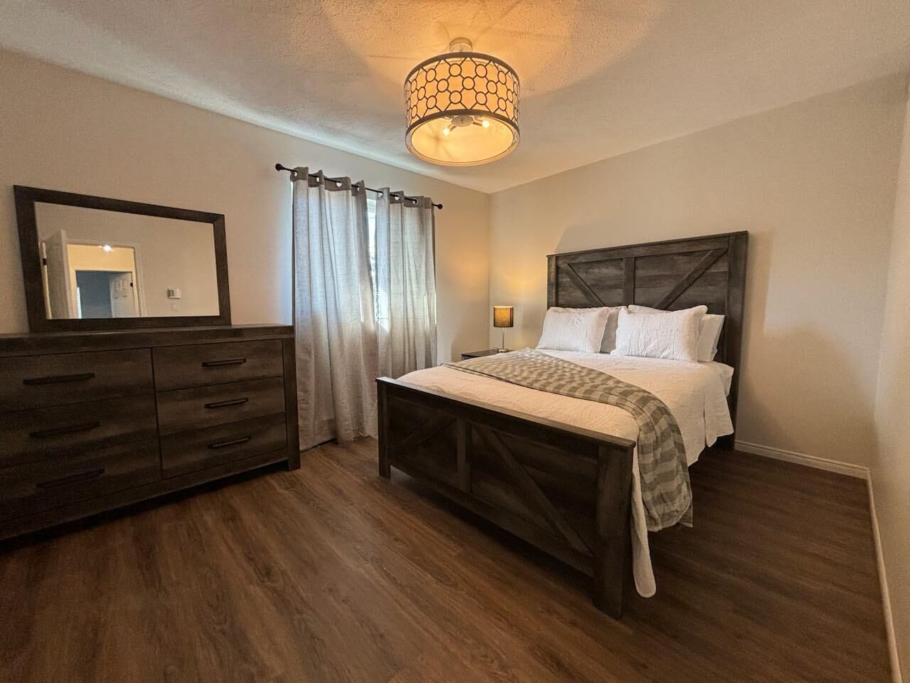 A bedroom with a bed, dresser, and a ceiling light fixture.