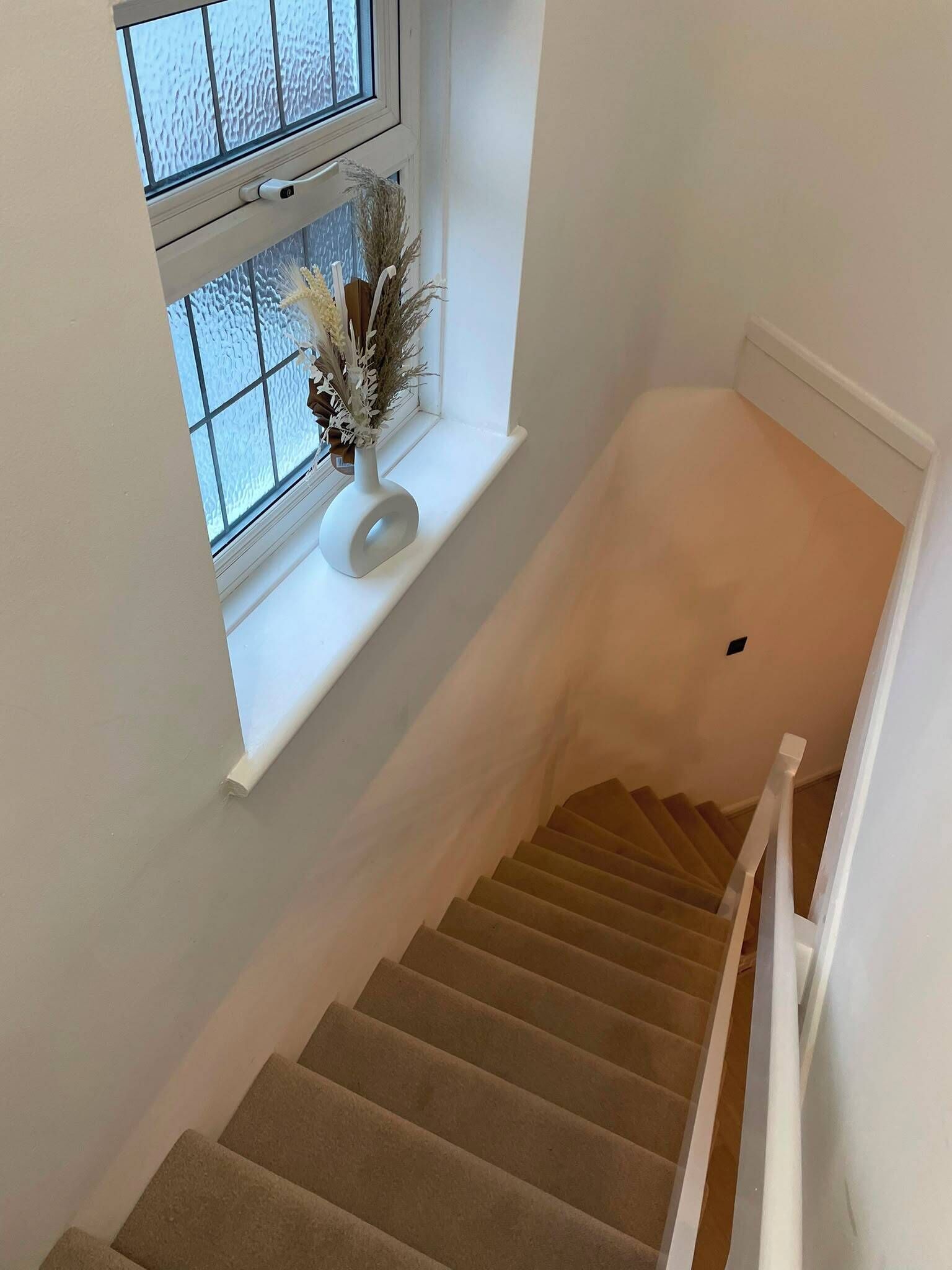 A staircase with carpeted steps leading to a landing.
