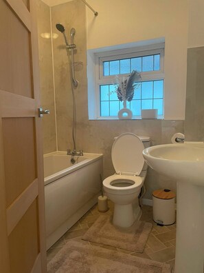 A bathroom with a bathtub, toilet, and sink. - Cosy cute modern square (Watford)