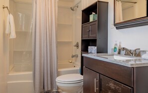 Ein Badezimmer mit Badewanne, Toilette und Waschtisch mit Spiegel.