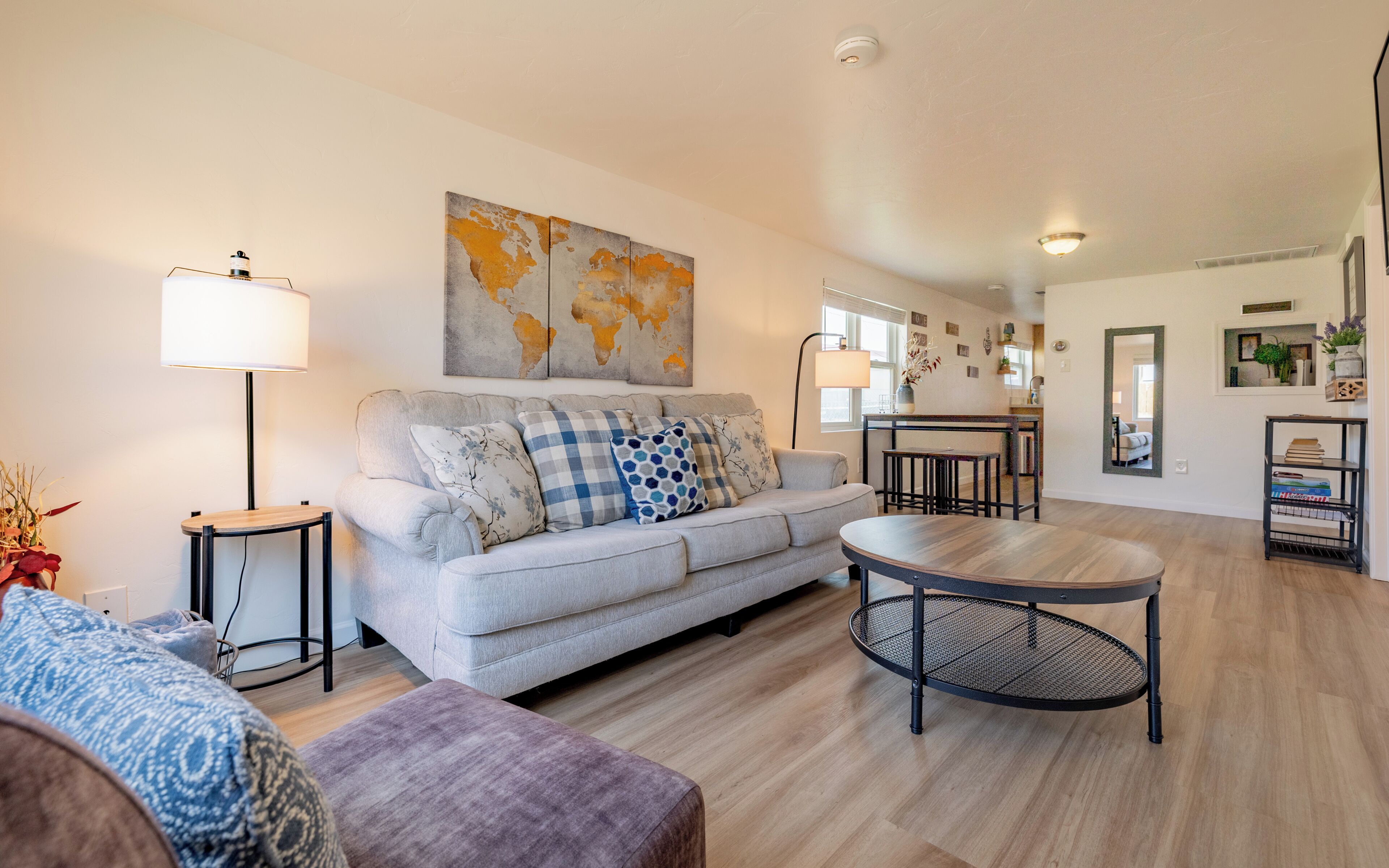 A living room with a sofa, a round coffee table, and a world map artwork on the wall.