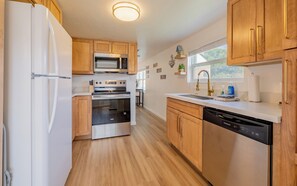A modern kitchen with wooden cabinets, stainless steel appliances, and a dishwasher. - Newly remodeled downtown Bleistein cottage 2bd/1 bath w/AC - sleeps up to 5! (Cody)