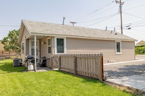 Ein eingeschossiges Haus mit überdachter Veranda, umzäunter Garten und Grill.