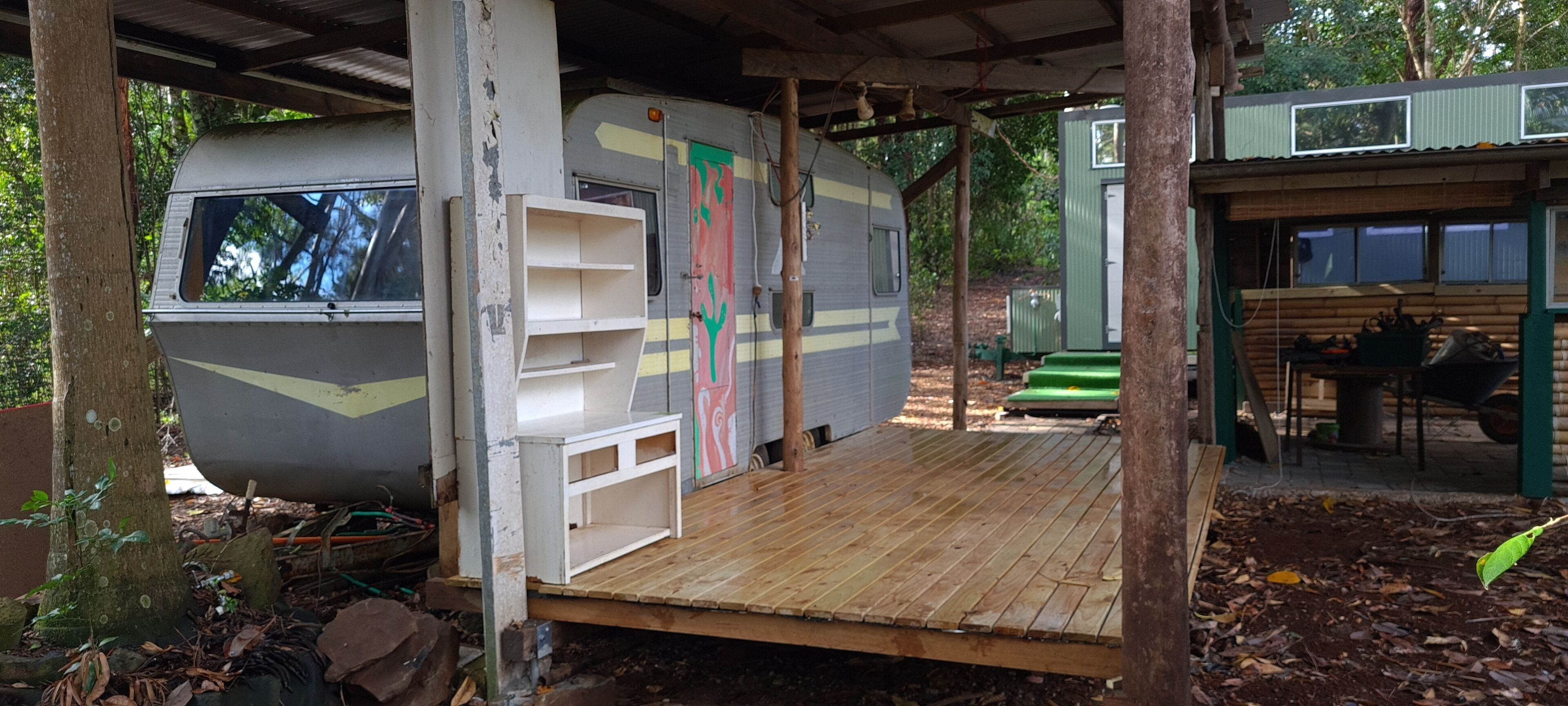 A mobile home with a wooden deck, a green door, and a window.