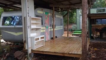 A mobile home with a wooden deck, a green door, and a window.