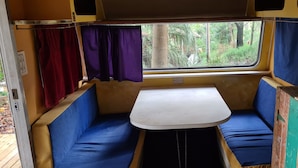 A compact interior with a small table and two blue cushioned seats.