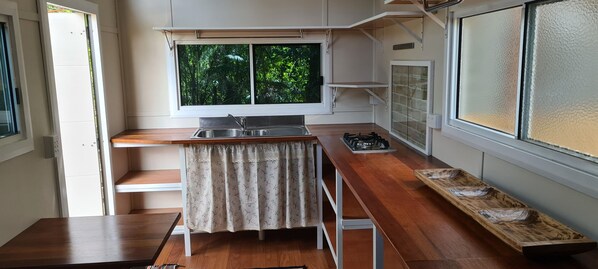 A compact kitchen with a window, a sink, and a stove.
