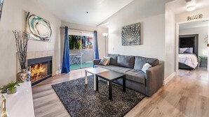 Una sala de estar moderna con chimenea, un sofá gris, una mesita de centro y vistas al exterior.