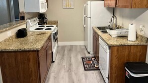 Una cocina compacta equipada con microondas, estufa, fregadero y lavavajillas.