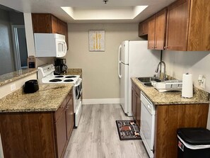 A compact kitchen with a microwave, stove, sink, and dishwasher. - Luxury 2BR/2BA Condo - Walk to the Strip, Rio & Palms! (Las Vegas)