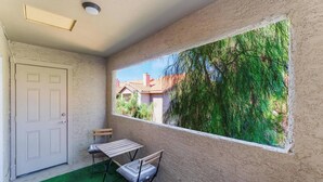 Una habitación con ventana, puerta, una pequeña mesa con sillas y alfombra verde.