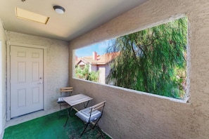 A room with a window, a door, a small table with chairs, and a green carpet. - Luxury 2BR/2BA Condo - Walk to the Strip, Rio & Palms! (Las Vegas)