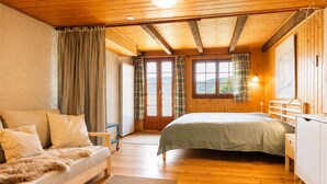 A cozy bedroom with a bed, a sofa, and a wooden ceiling. - Outside: Apartment located on the ground floor of a chalet, with private garden, outdoor furniture a (St-Luc)