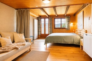 Ein gemütliches Schlafzimmer mit einem Bett, einer Couch und einer Holzbalkendecke.
