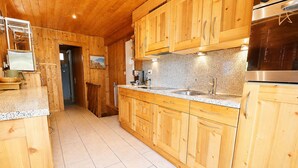 A wooden kitchen with a granite countertop, stainless steel appliances, and a tiled floor. - Outside: Apartment located on the ground floor of a chalet, with private garden, outdoor furniture a (St-Luc)