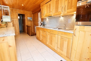 Eine Holz-Küche mit Granit-Arbeitsplatte, Edelstahlgeräten und einem gefliesten Boden.