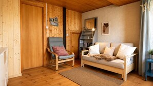 A wooden interior with a sofa, a chair, a rug, and a small table with a plant. - Outside: Apartment located on the ground floor of a chalet, with private garden, outdoor furniture a (St-Luc)