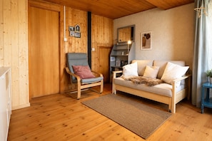 Ein Holzinterieur mit einer Couch, einem Sessel, einem Teppich und einem kleinen Tisch mit einer Pflanze.