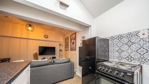 Una cocina moderna con horno empotrado, refrigerador negro y un rincón comedor con sofá.