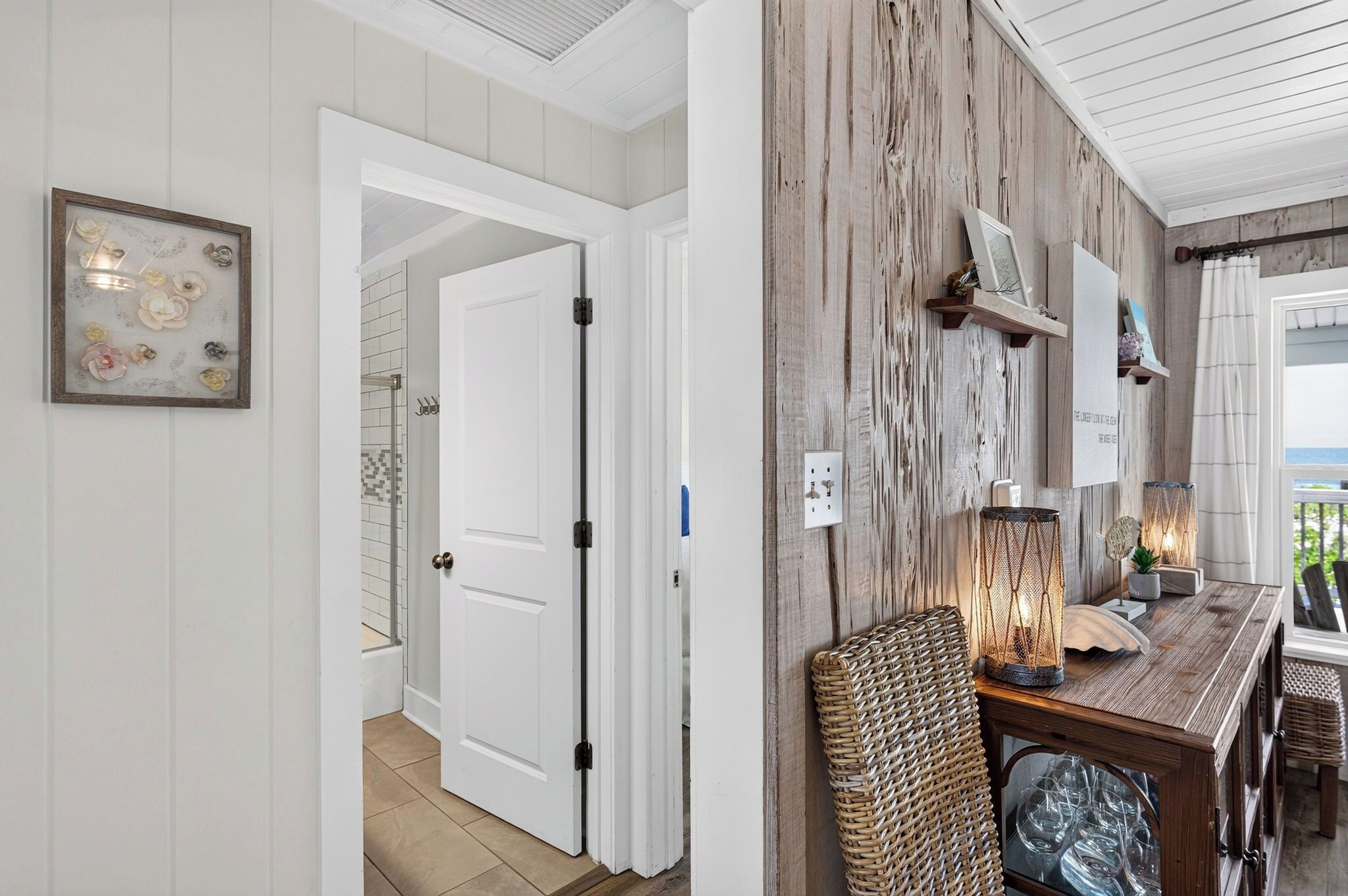 A hallway with a white door, a framed artwork, and a rustic wall with shelves.