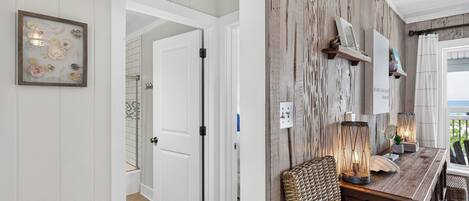 A hallway with a white door, a framed artwork, and a rustic wall with shelves.
