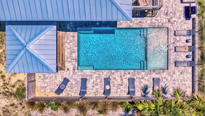 Et tagområde med swimmingpool, flere liggestole og en lille terrasse med borde og stole.
